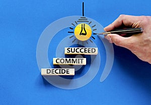 Decide commit succeed symbol. Concept word Decide Commit Succeed on beautiful wooden block. Businessman hand. Beautiful blue table