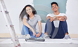 We decided to paint the house ourself. a young couple painting a wall in a room together.