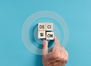 Decision making in business. Male hand placing wooden blocks into a square shape to assemble the word Decision