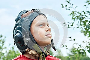 Decisive boy in vintage pilot helmet looks into sky in park