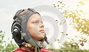 Decisive boy in vintage pilot helmet looks into sky in park