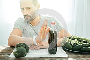 Decisive serious man sitting and refusing to drink.