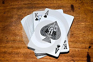 Deck of cards with Ace of spades at front  in wooden background.