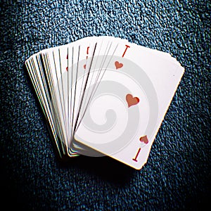 Deck of cards on a dark gray table, ace of hearts first