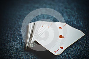 A deck of cards on a dark table, ace of hearts first, side view, closeup