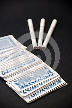 Deck of cards and three cigarettes spilled on the black background
