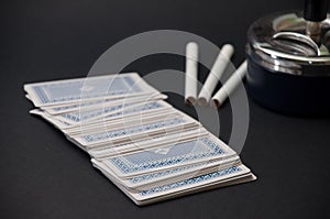 Deck of cards and three cigarettes spilled on the black background