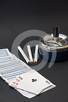 Deck of cards and three cigarettes spilled on the black background