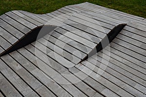 Deck chair composed of three waves which are made of wood and board. large seating elements in a landscape park. furniture for ten