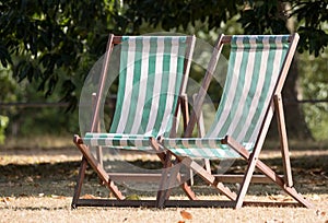 Deck chairs with green and white stripes on dead grass in Hyde Park, London during the summer heatwave, July 2018.