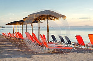 Deck chairs and parasols on sea beach in summer