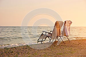 Deck chairs with towels on backrest on the seashore.