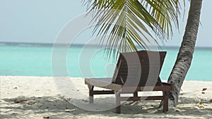 Deck chairs in tropical island at sandy coast by ocean. Zanzibar. Wooden sun loungers in the shade of straw parasol by