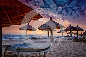 Deck chairs with umrellas on the beach with beautiful sunset in Senegal, Africa. There is blue sky and golden and red sun. It is