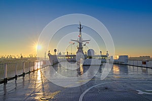 Deck of a cruise liner setting at the port against the background of the morning rising sun