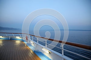 Deck of a cruise ship looking out to sea at twilight time. Ocean is very calm & tranquil