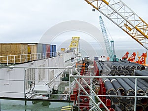 The deck lay barge. Pipes and Lifting cranes on the ship. Equipment for laying a pipeline on the seabed