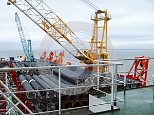 The deck lay barge. Pipes and Lifting cranes on the ship. Equipment for laying a pipeline on the seabed