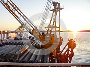 The deck lay barge. Pipes and Lifting cranes on the ship. Equipment for laying a pipeline on the seabed