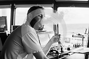 Deck navigation officer smokes a wad on the navigation bridge of yacht