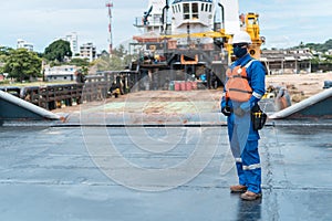 Deck officer with protective mask standing in the loading port facing away from the ship