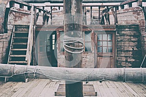 The deck of an old sailboat with a mast in the center, a ladder and hold windows. Vintage wooden ship, close-up