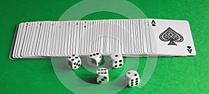 A deck of playing cards and dice on a green table