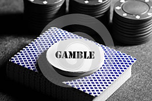 Deck of playing cards with a token on top with the word gamble and casino chips