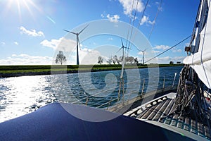 Deck of a sailing yacht with windmills in the background with a beautiful clouded sky above.