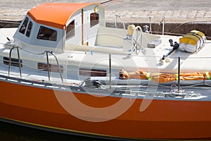 The deck of a small orange boat at the harbor