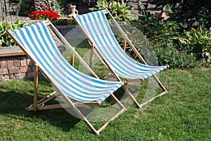 Deckchair chaise chair in cafe garden park grass, with blue red stripes relax