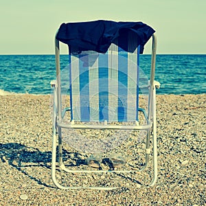 Deckchair and man swimsuit on the beach, with a retro effect