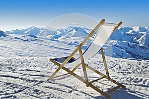 Deckchair in the snow facing the Alps