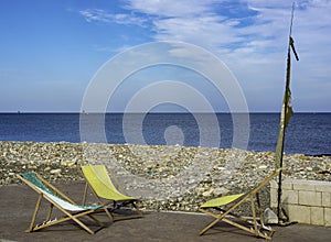 Deckchairs abandoned beside a pebble beach