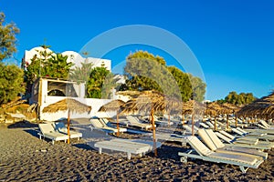 Deckchairs on peaceful morning beach Kamari Black beach Santorini Greece