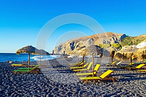 Deckchairs on peaceful morning beach Kamari Black beach Santorini Greece