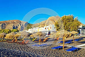 Deckchairs on peaceful morning beach Kamari Black beach Santorini Greece