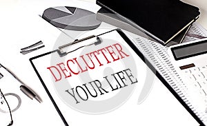 DECLUTTER YOUR LIFE text on paper clipboard with chart and notebook on withe background