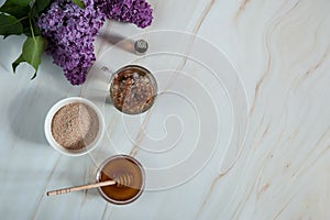 Decoction of lilac flowers Syringa vulgaris, oat bran, honey and essential oil on a marble background.