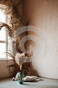 Decor, dry flowers in the corner of the room in a light style. sunny room with panoramic windows. Scandinavian style in the interi