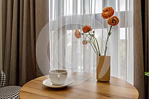 Decor elements of the guest room and rest room with a tea table, an armchair and a bouquet of flowers and a cup of coffee