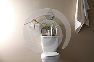 Decor elements, necessities and toilet bowl near beige wall. Bathroom photo