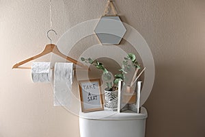 Decor elements, necessities and toilet bowl near beige wall photo