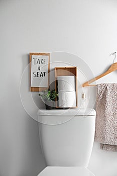 Decor elements, necessities and toilet bowl near wall. Bathroom interior photo