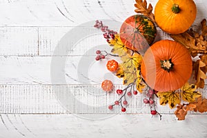 Decor from pumpkins, berries and leaves on white rustic wooden background. Concept of Thanksgiving day or Halloween. Top view