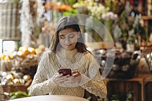 In the decor store, a beautiful young woman is seen with her phone.