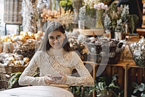 In the decor store, a young woman is seen holding her phone.