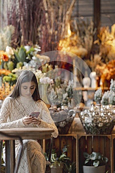 In the decor store, a young woman is seen holding her phone.