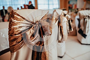 Decor of wedding chairs in gold tones. Decoration of halls for events. Wedding concept