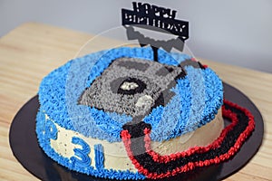 Decorated birthday cake with happy birthday stick pinned. Camera-themed round cake for the 31st birthday celebration for the